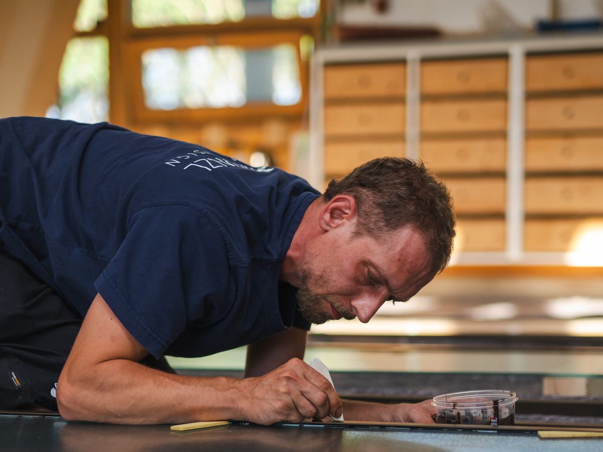 Mitarbeiter von GLAS KÜNZL zeichnet in der Werkstatt auf der Werkbank an